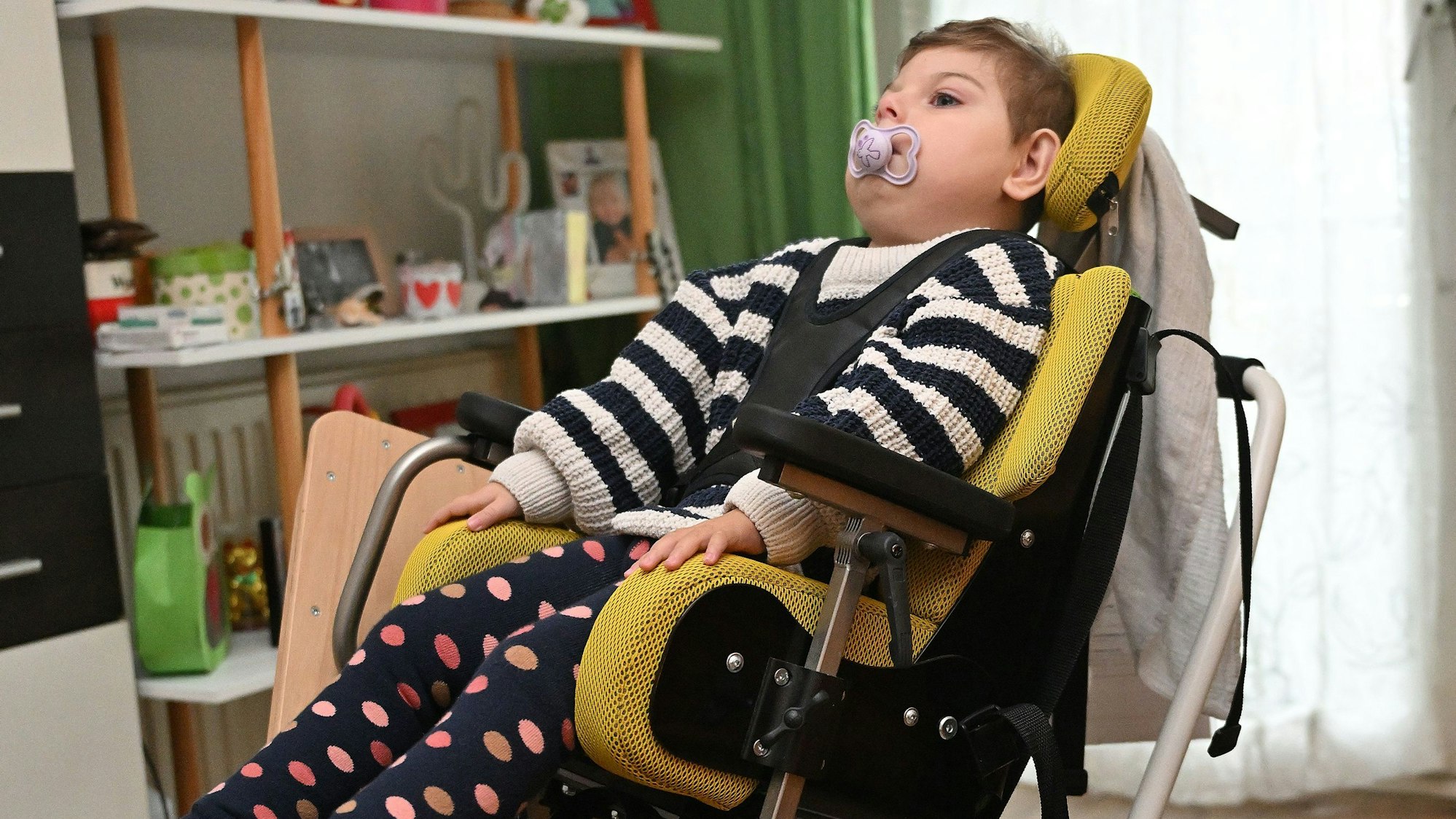 Josefine kann sich nicht selbst aufrecht halten, da ihre Muskeln nicht stark genug sind. Deswegen wird sie in ihrem Stuhl angeschnallt.