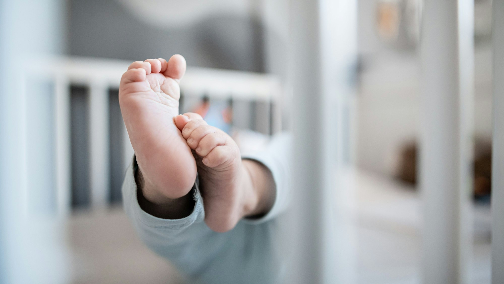 Füße eines Babys in einem Beistellbett