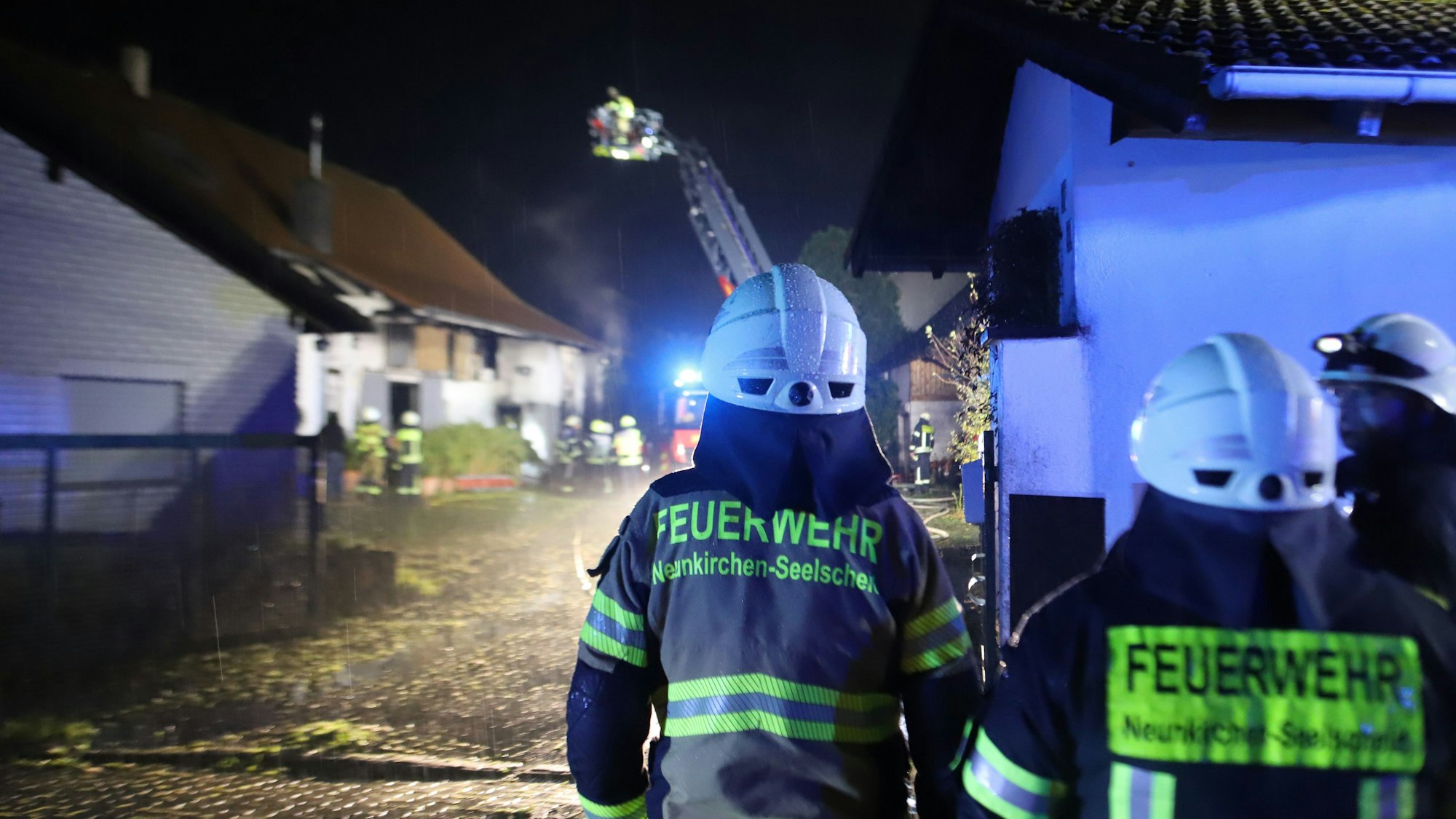 Vorne beobachten Feuerwehrleute die Drehleiter, die im Hintergrund an das Dach herangefahren wurde.