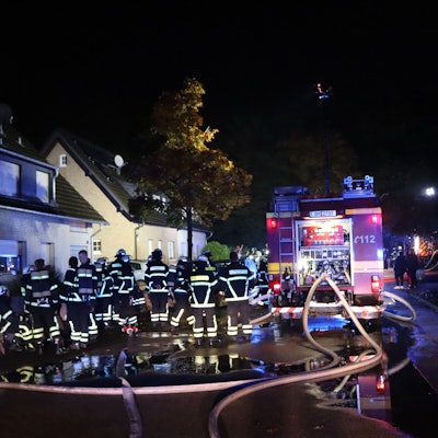 Dutzende Feuerwehrleute stehen auf einer Straße.