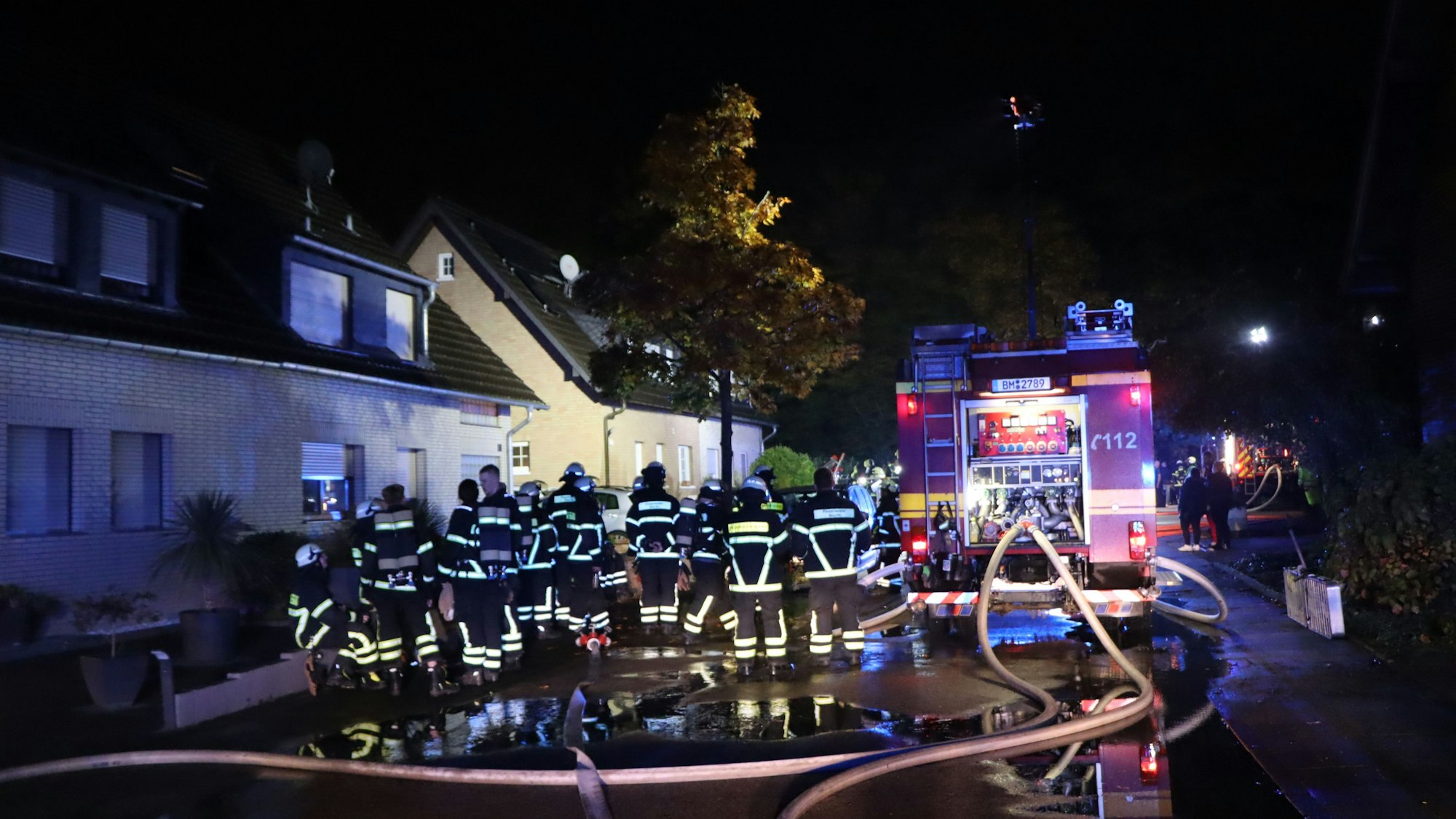Dutzende Feuerwehrleute stehen auf einer Straße.