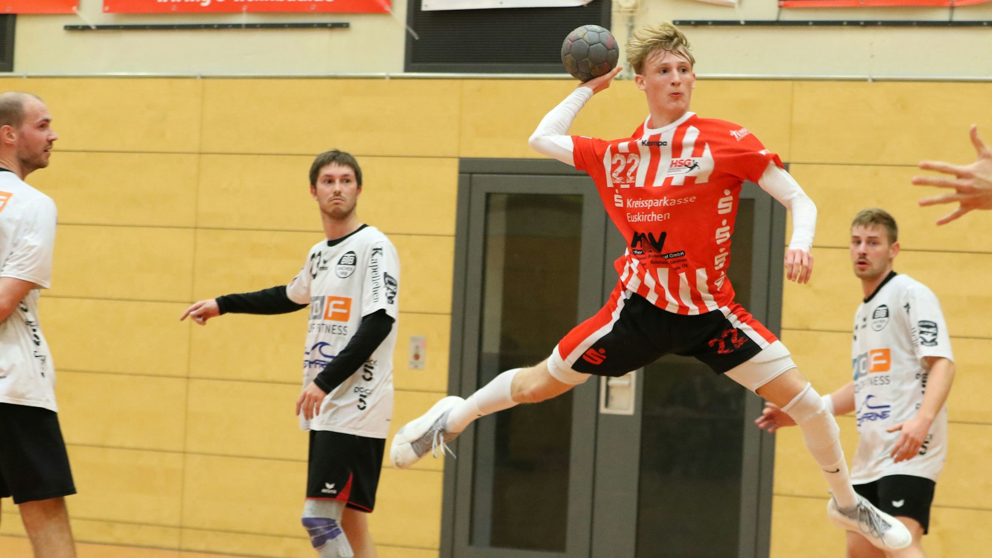 Ein junger Handballer beim Sprungwurf. Drei Verteidiger schauen zu.