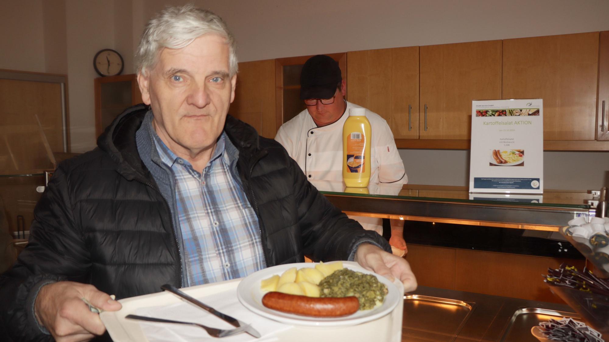 Ein Mann hält ein Tablett mit Essen in den Händen.