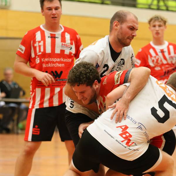 Ein Handballer versucht, sich gegen zwei Gegner durchzusetzen, die ihn aber in die Zange nehmen.