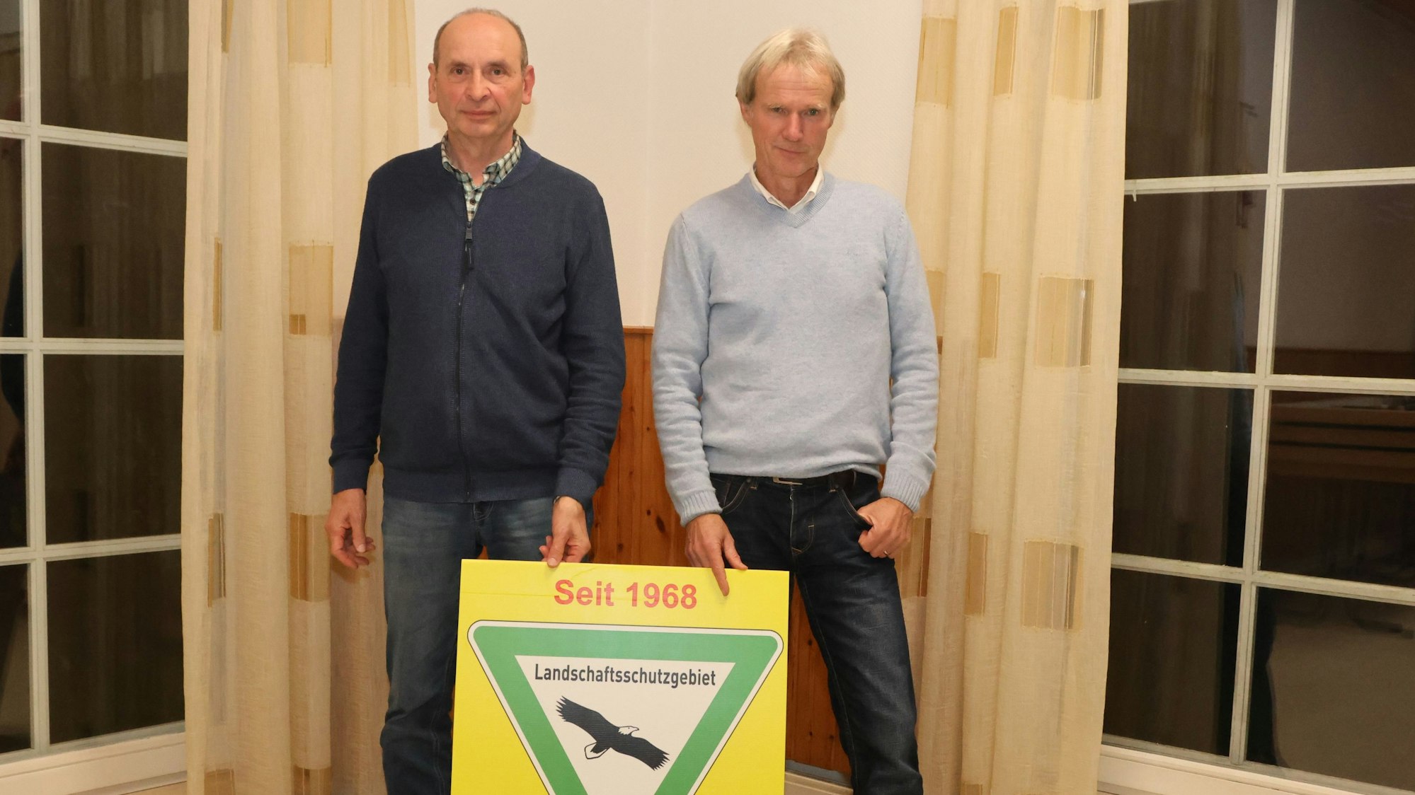 Horst Braun (links) und Christoph Gehrke von der Bürgerinitiative Wildburger Land informierten über den Stand der Dinge beim Bau von Windkraftanlagen in der Ortschaft Steeg. Unser Foto zeigt die beiden Männer mit einem Schild aus dem Landschaftsschutz.