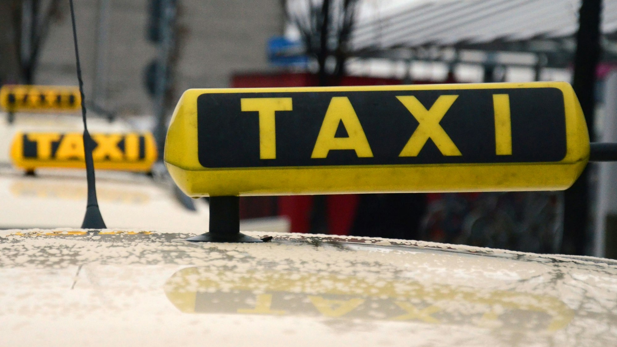 Das Symbolbild zeigt die Taxischilder von drei Taxis, die in einer Reihe stehen.