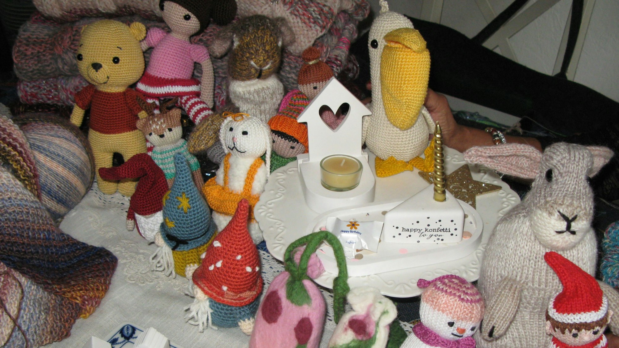 Kleine Püppchen, Tierfiguren, die aus Wolle gehäkelt sind, und Dekoratives mit Kerzen.