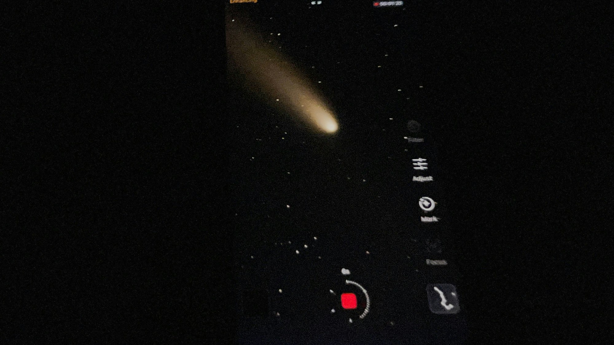 Auf einem Handy-Bild-Schirm ist der Komet zu sehen.