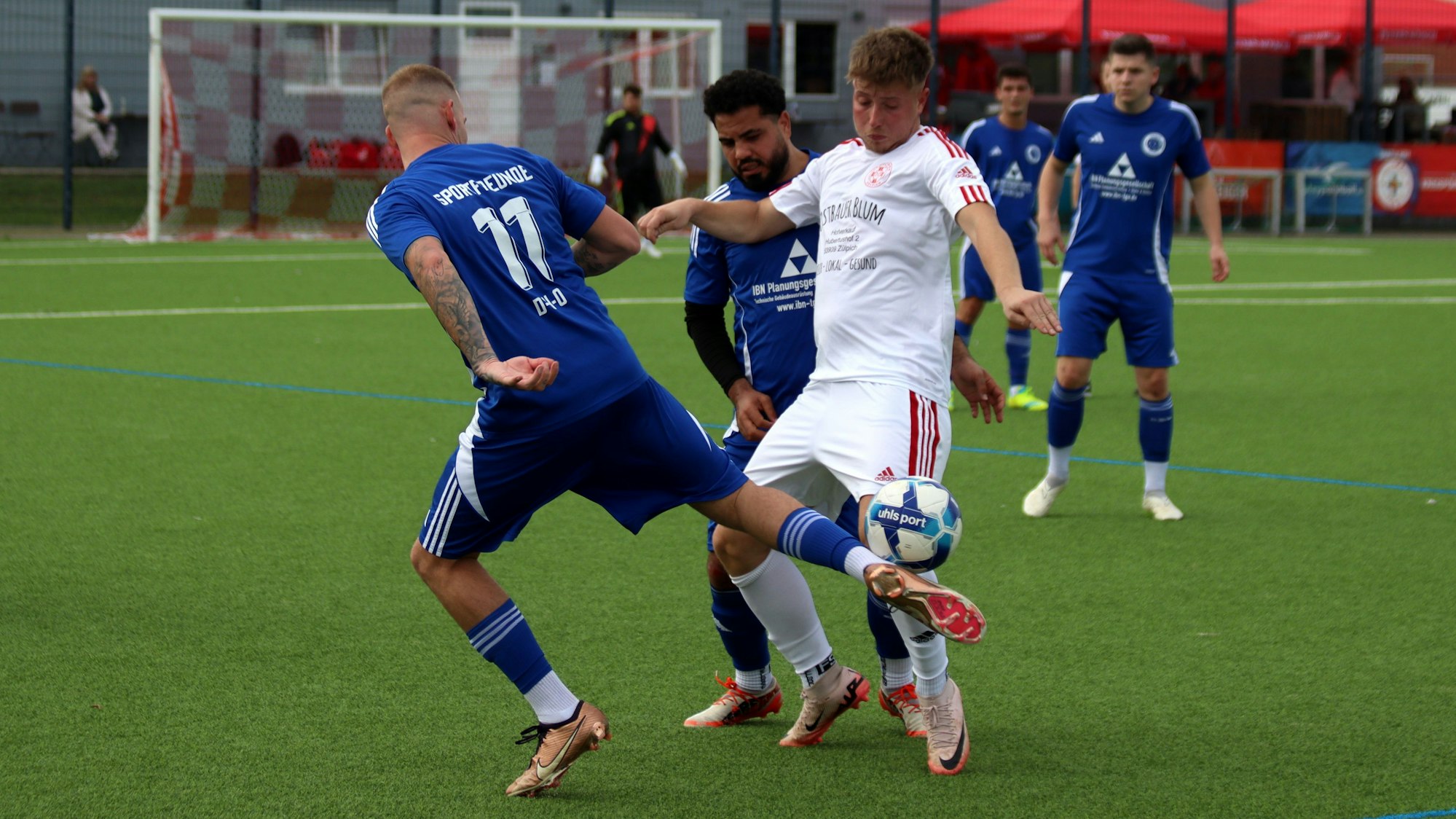 Ein Spieler behauptet den Ball, obwohl er von vorne und von hinten attackiert wird.