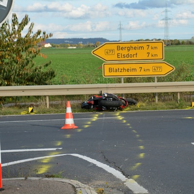 Das verunfallte Motorrad liegt im Seitenstreifen vor der Leitplanke und Verkehrsschildern.