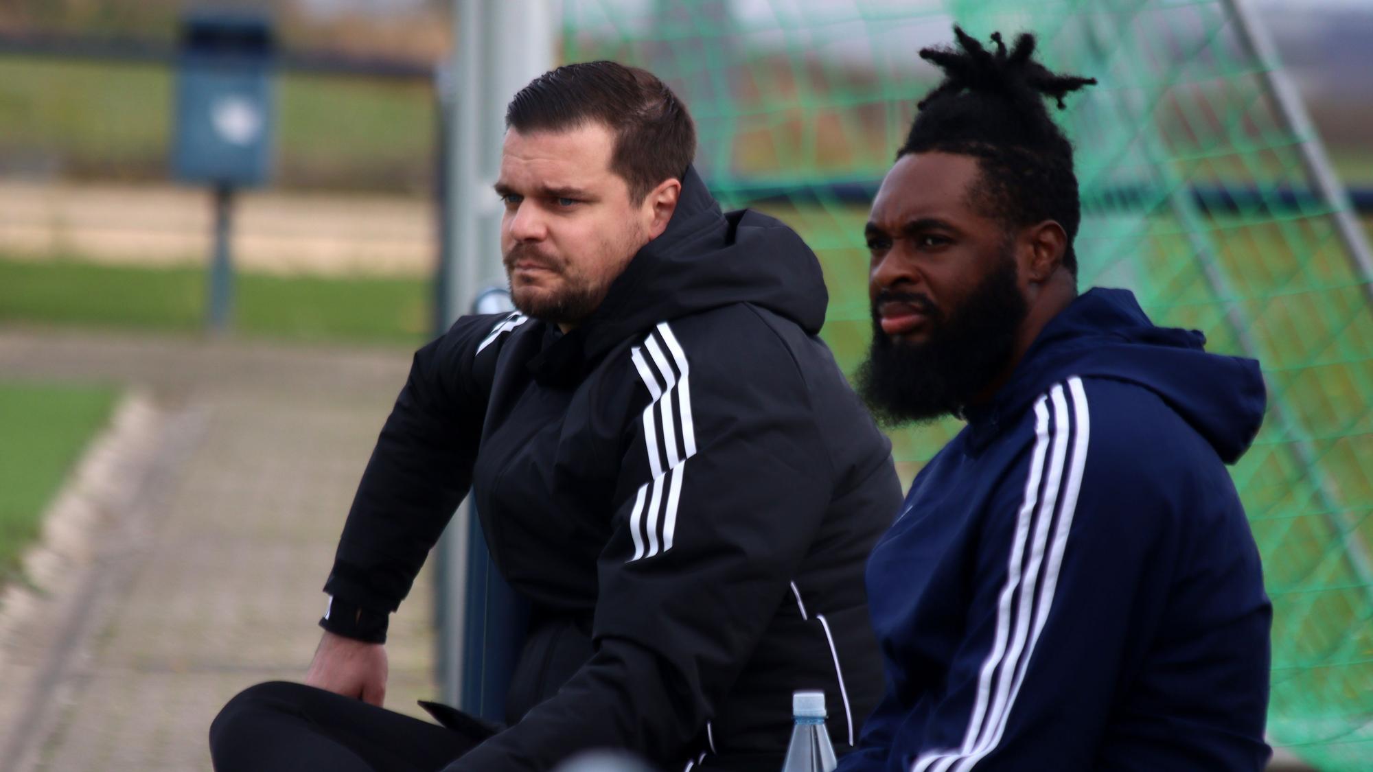 Der Trainer der Sportfreunde D-H-O sitzt neben einem Ersatzspieler.