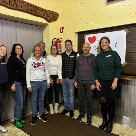 Unter der Leitung von Elisabeth Weißner (links) und Julia Wäger (rechts) von der Projektagentur Oberberg fand in Waldbröl-Schönenbach ein Workshop zur Sanierung des Dorfgemeinschaftshauses statt. Hier posiert die ganze Gruppe vor der Küche des Hauses.
