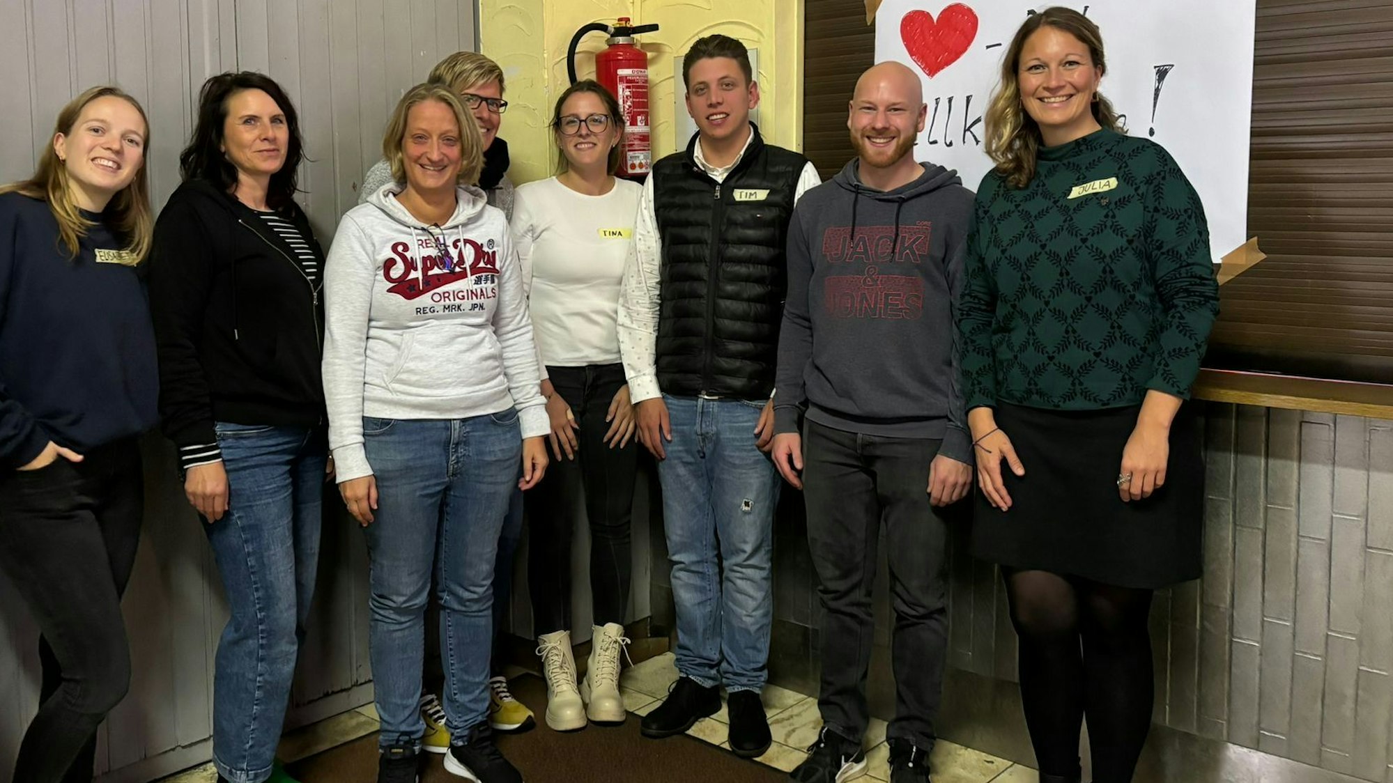 Unter der Leitung von Elisabeth Weißner (links) und Julia Wäger (rechts) von der Projektagentur Oberberg fand in Waldbröl-Schönenbach ein Workshop zur Sanierung des Dorfgemeinschaftshauses statt. Hier posiert die ganze Gruppe vor der Küche des Hauses.