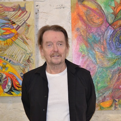 Ein Mann steht vor zwei Gemälden.