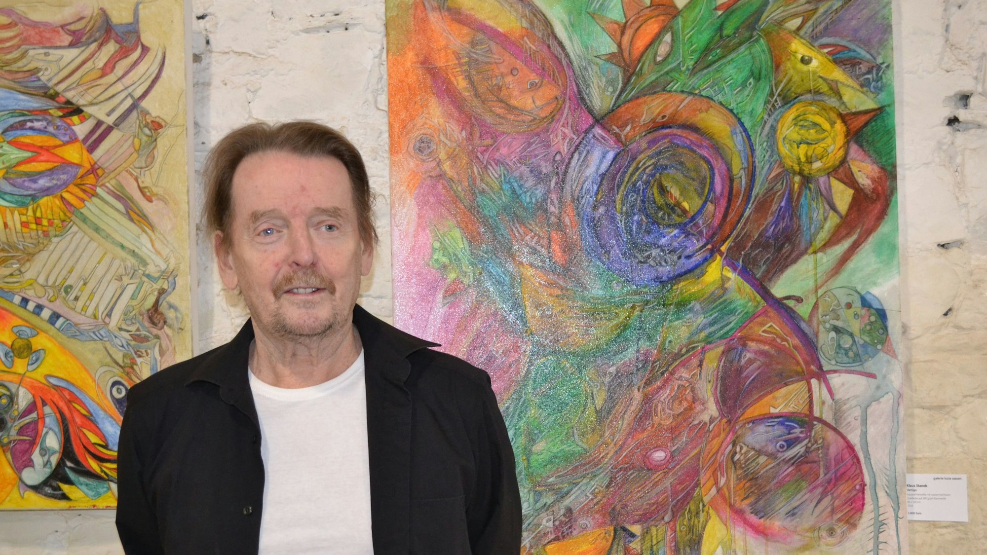 Ein Mann steht vor zwei Gemälden.