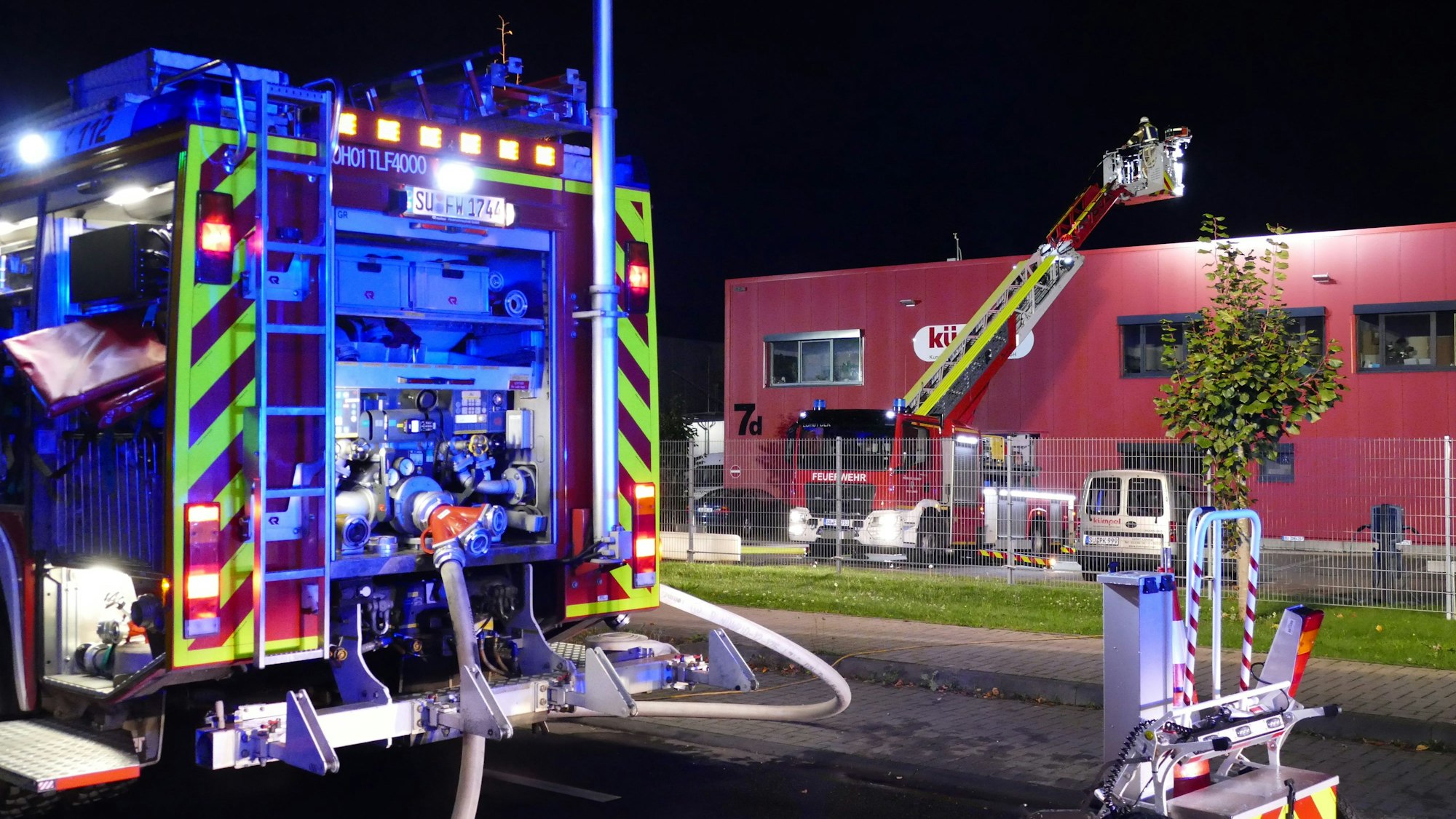Ein Löschfahrzeug der Feuerwehr im Vordergrund, im Hintergrund die Drehleiter im Einsatz.