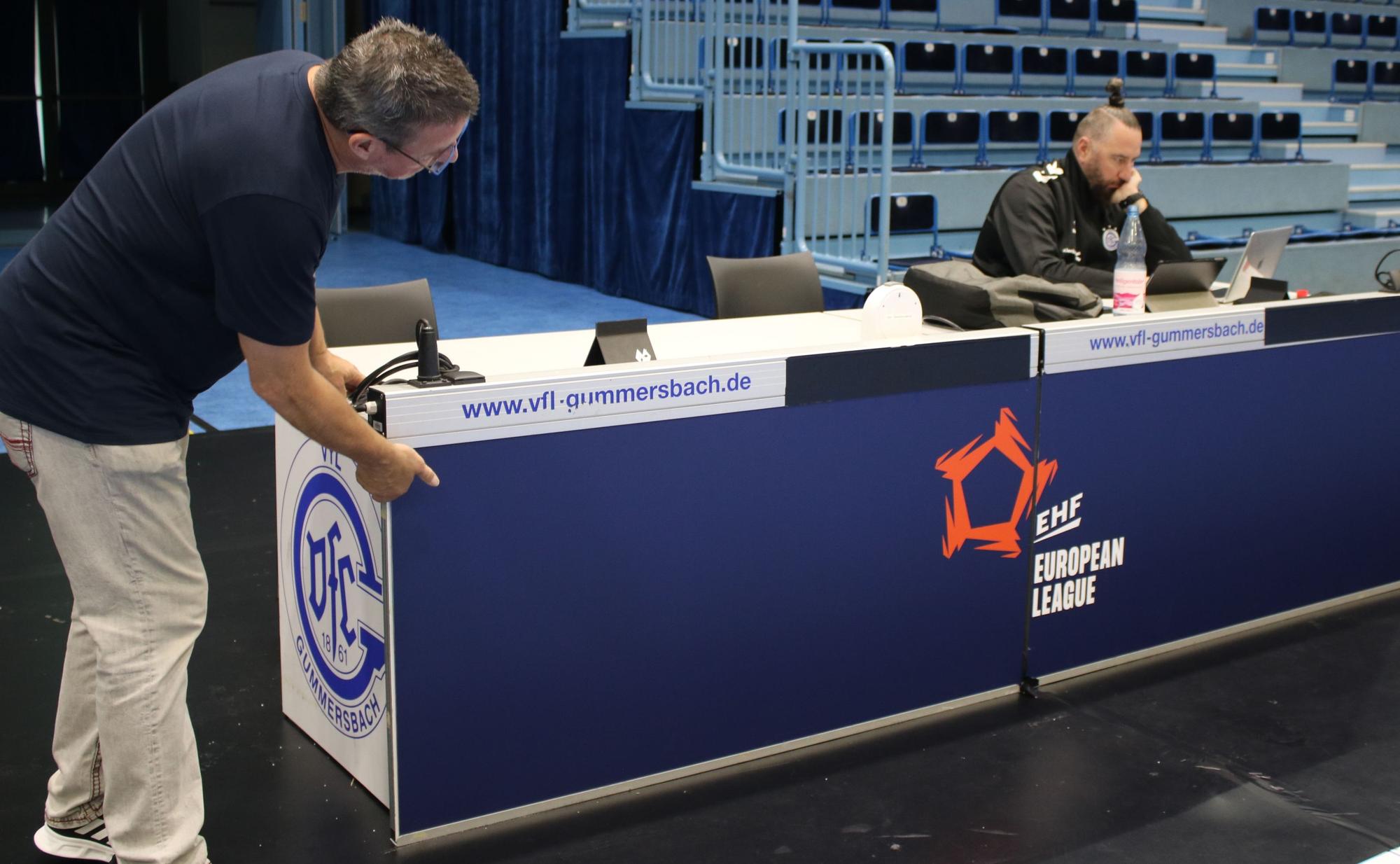 Thomas Knoblich betrachtet, ob die beiden blauen Platten und das zusammengeschobene EHF-Logo.