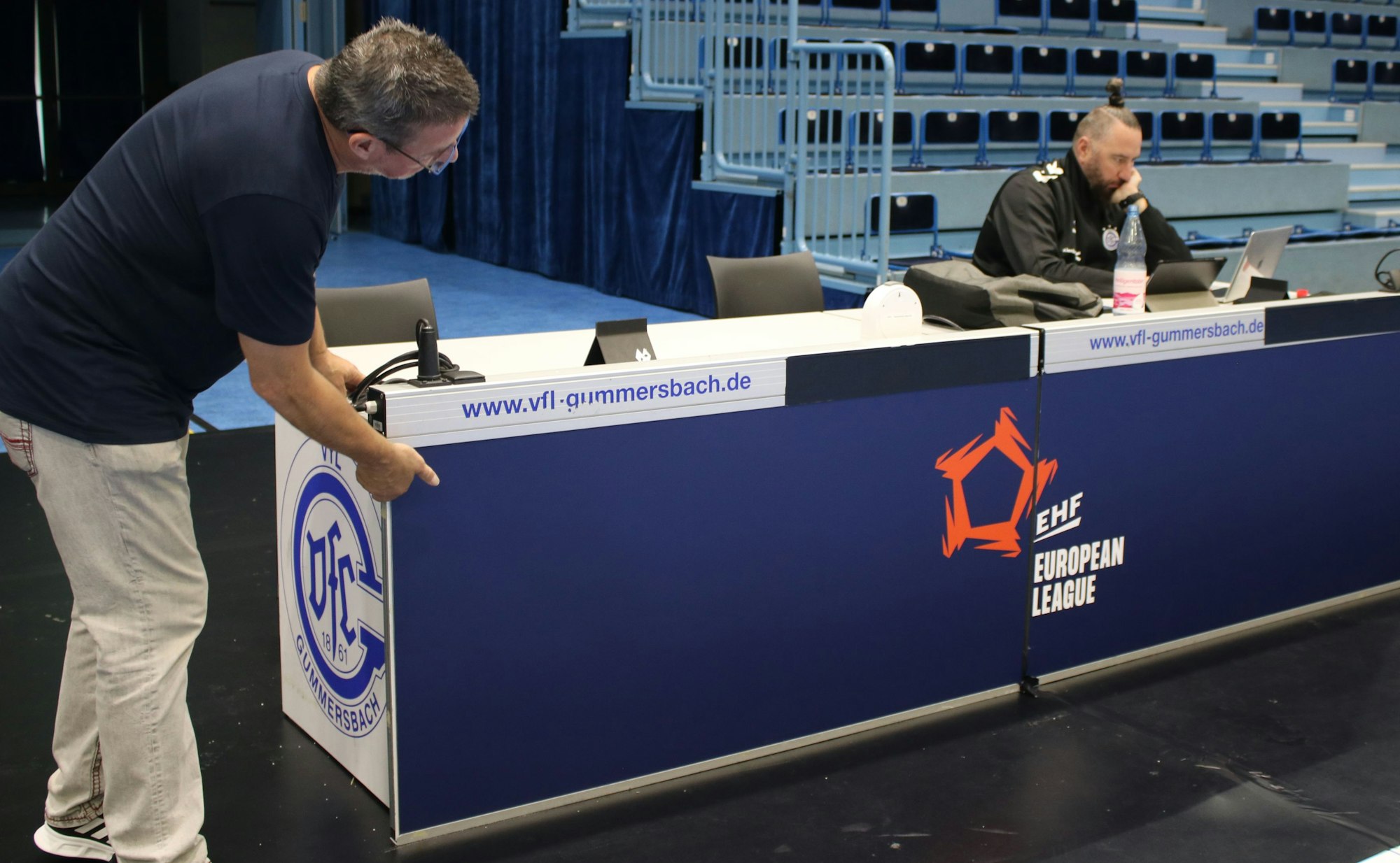 Thomas Knoblich betrachtet, ob die beiden blauen Platten und das zusammengeschobene EHF-Logo.