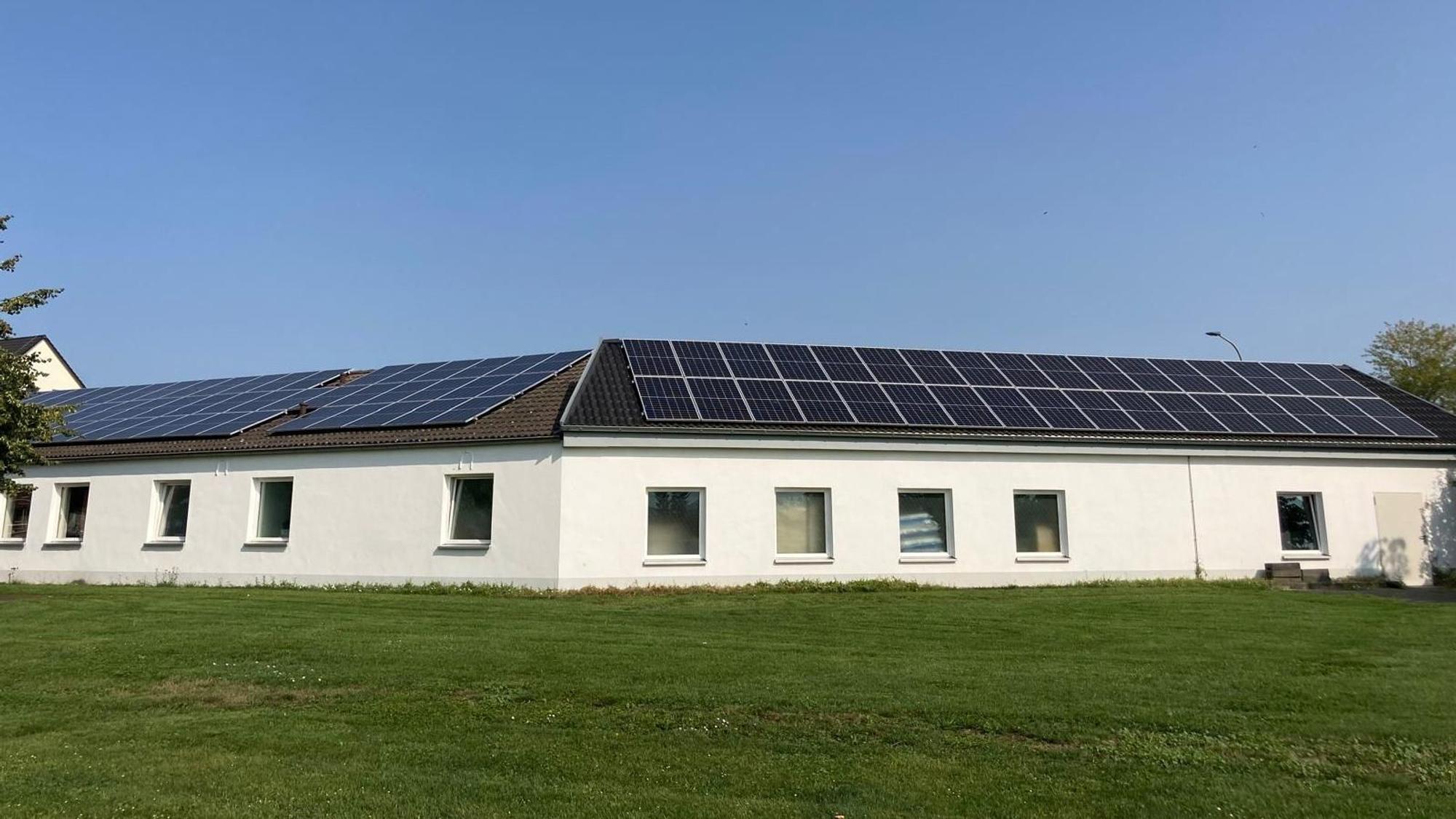 Auf dem Dach eines Gebäudes befinden sich Photovoltaik-Module.