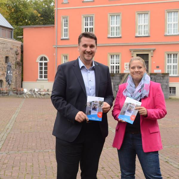 Ein Mann und eine Frau stehen vor einem alten Herrenhaus.