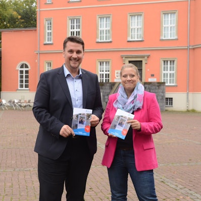Ein Mann und eine Frau stehen vor einem alten Herrenhaus.