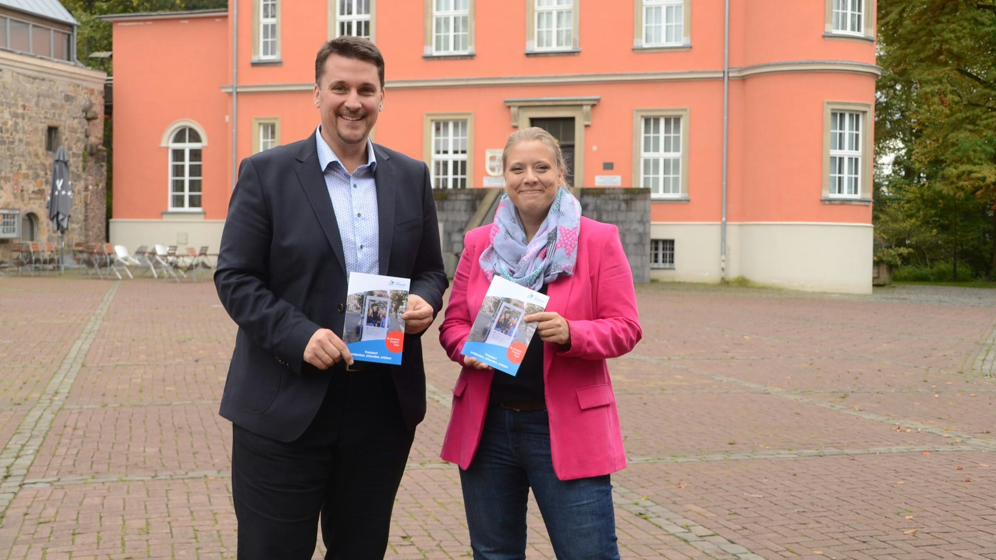 Ein Mann und eine Frau stehen vor einem alten Herrenhaus.