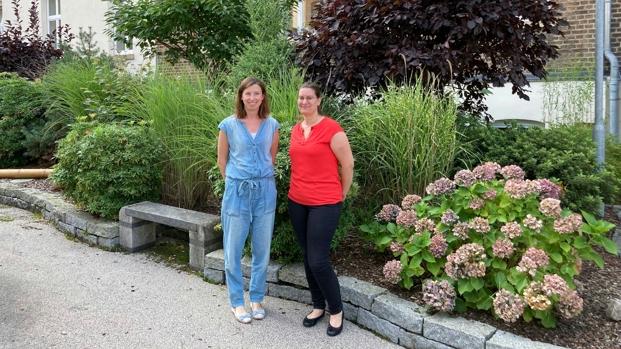 Zwei Personen stehen in einem begrünten Hof.