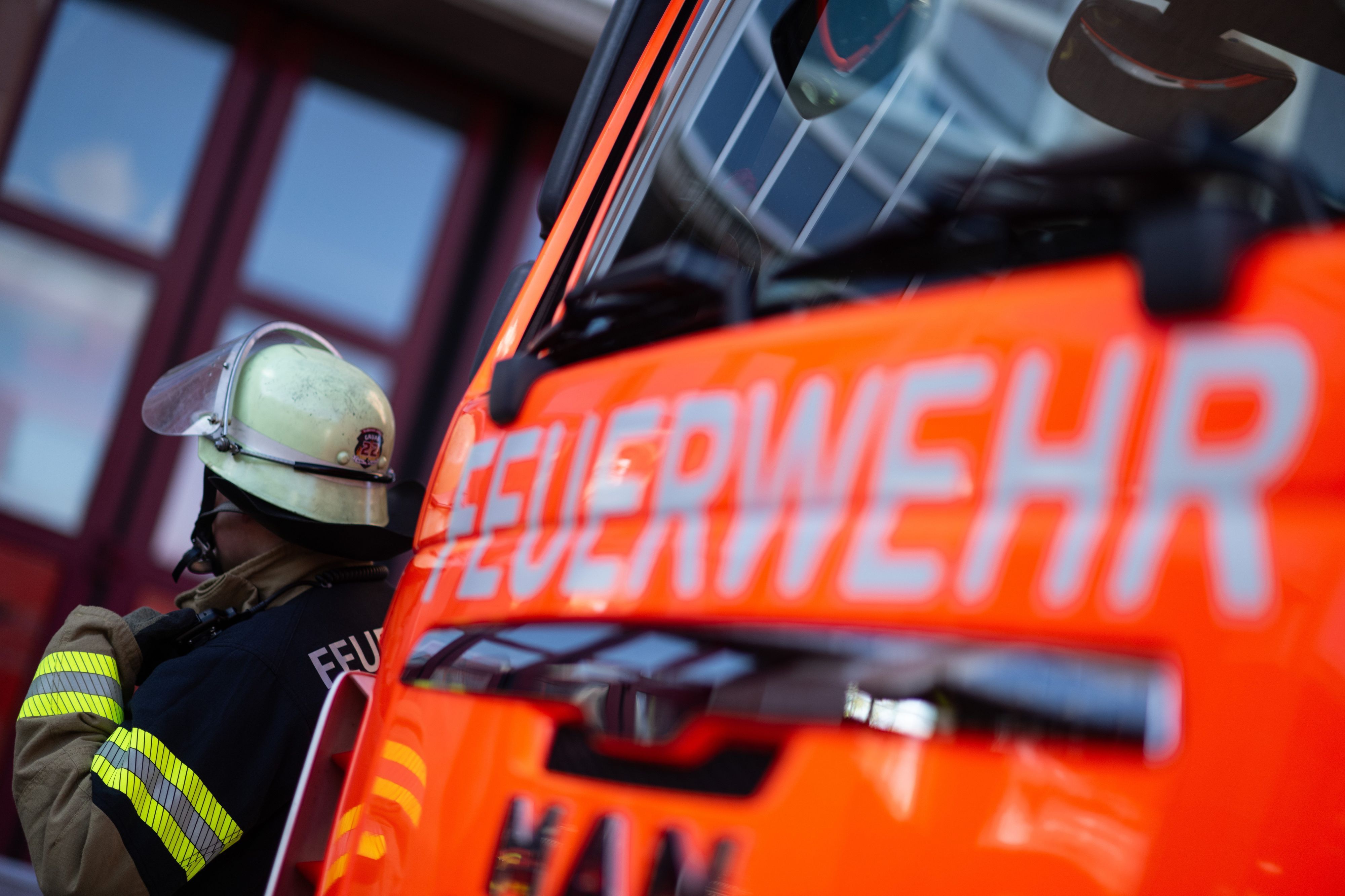 08.11.2023, Baden-Württemberg, Stuttgart: Eine Einsatzkraft der Feuerwehr steht neben einem Einsatzfahrzeug der Feuerwehr.