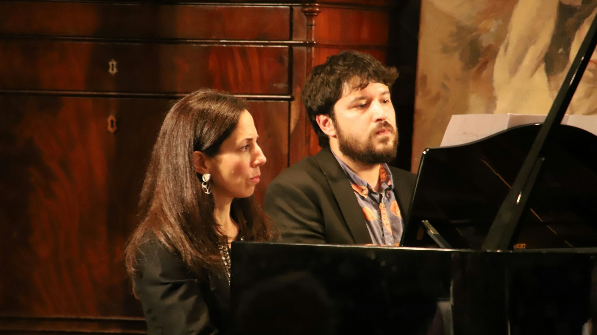 Eine Frau und ein Mann spielen gemeinsam am Klavier.
