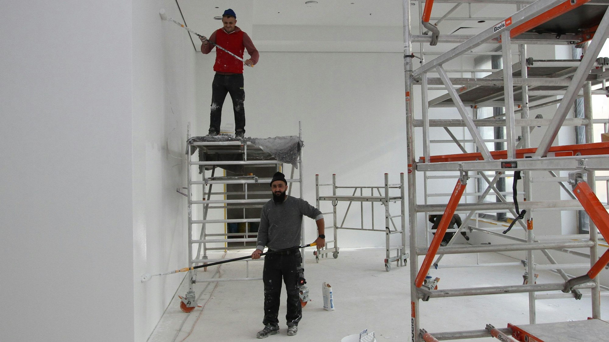 Maler und Gerüste in einem hellen Raum.