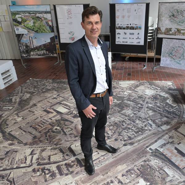 Oliver Brügge bei seiner Vorstellung im Oktober 2024. Er steht auf einem Foto der 36 Hektar großen Industriebrache.