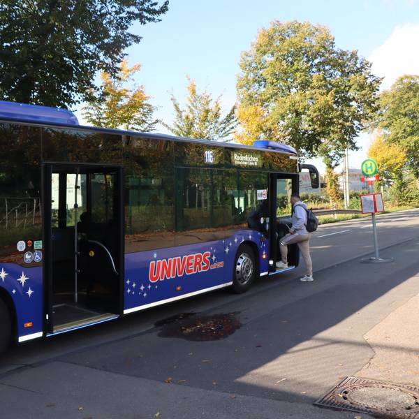 Ein Bus steht an einer Haltestelle, ein Mann steigt ein.