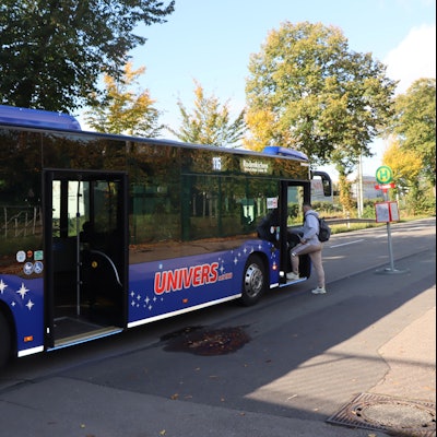 Ein Bus steht an einer Haltestelle, ein Mann steigt ein.