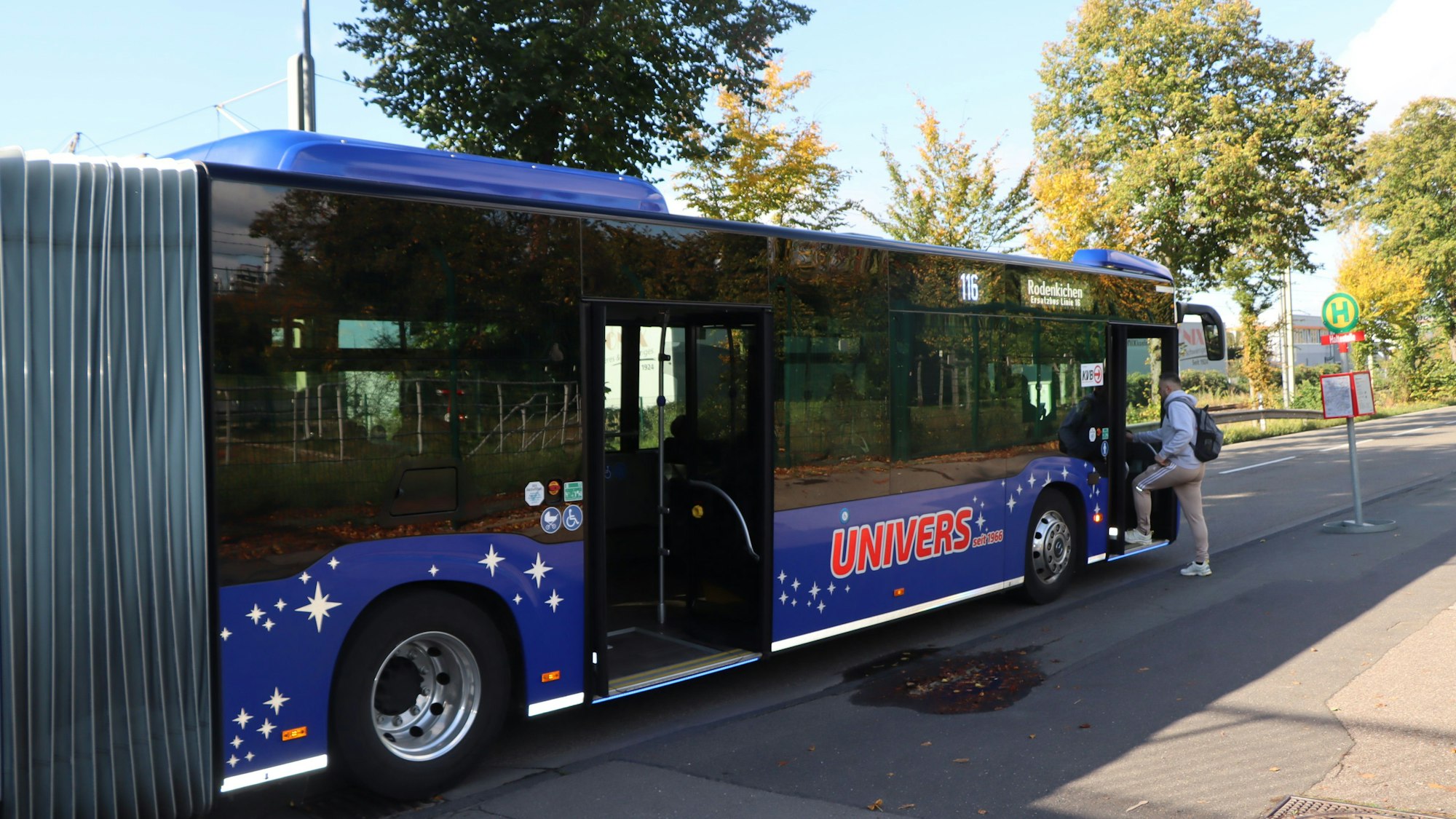 Ein Bus steht an einer Haltestelle, ein Mann steigt ein.