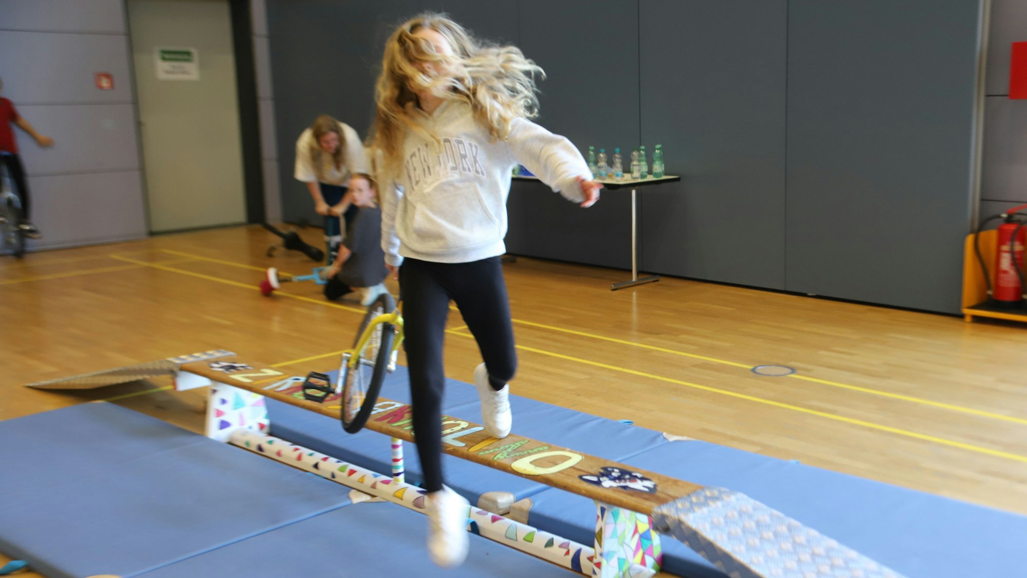 Ein Mädchen springt mit ihrem Einrad von einer Bank.