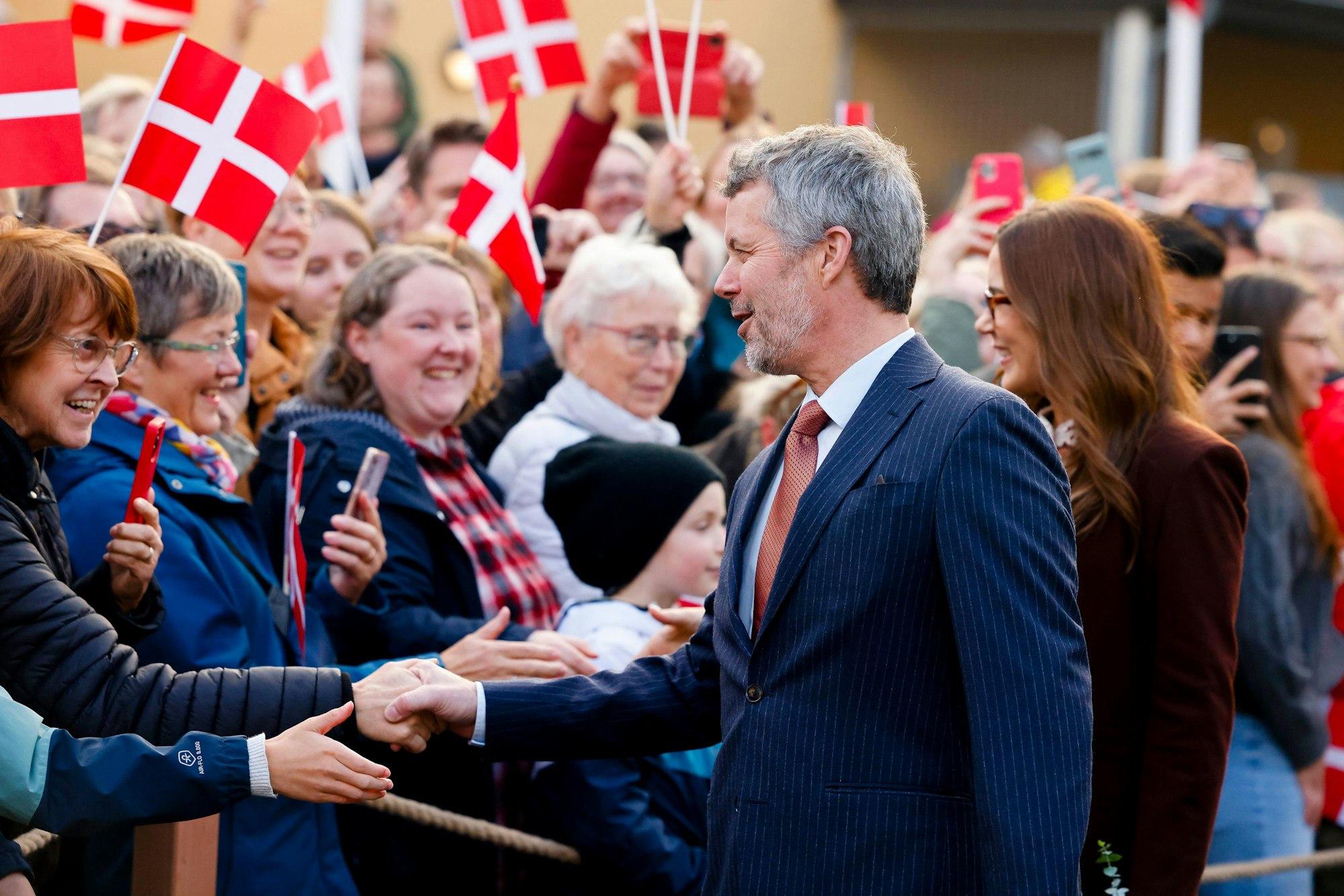 Dänemarks König Frederik X. (l) und Königin Mary verabschieden sich von den Zuschauern vor dem Flensborghus. Das Königspaar kam zu einem Treffen mit Vertretern der dänischen Minderheit
