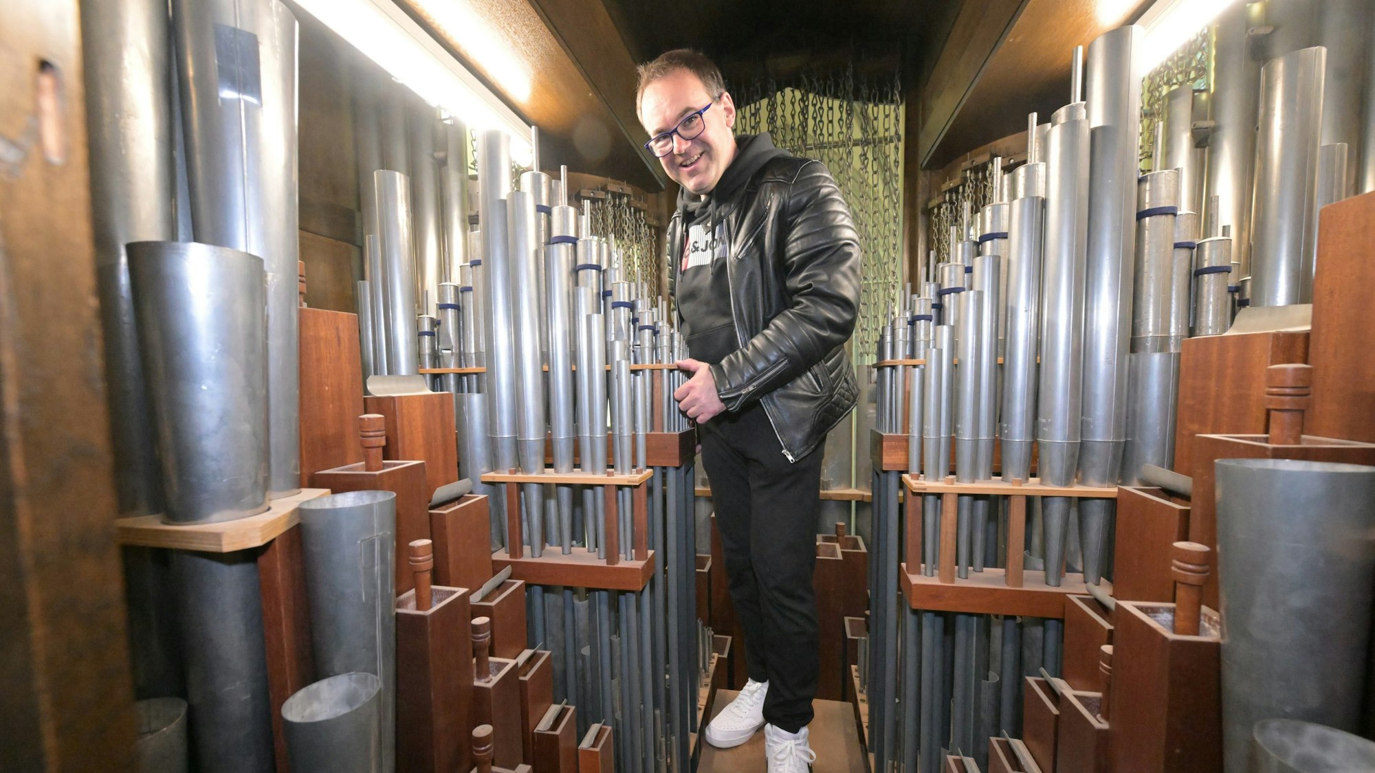 Domorganist Rolf Müller im Innern der Klais-Orgel im Altenberger Dom. Man sieht zahlreiche Orgelpfeifen aus Metall.