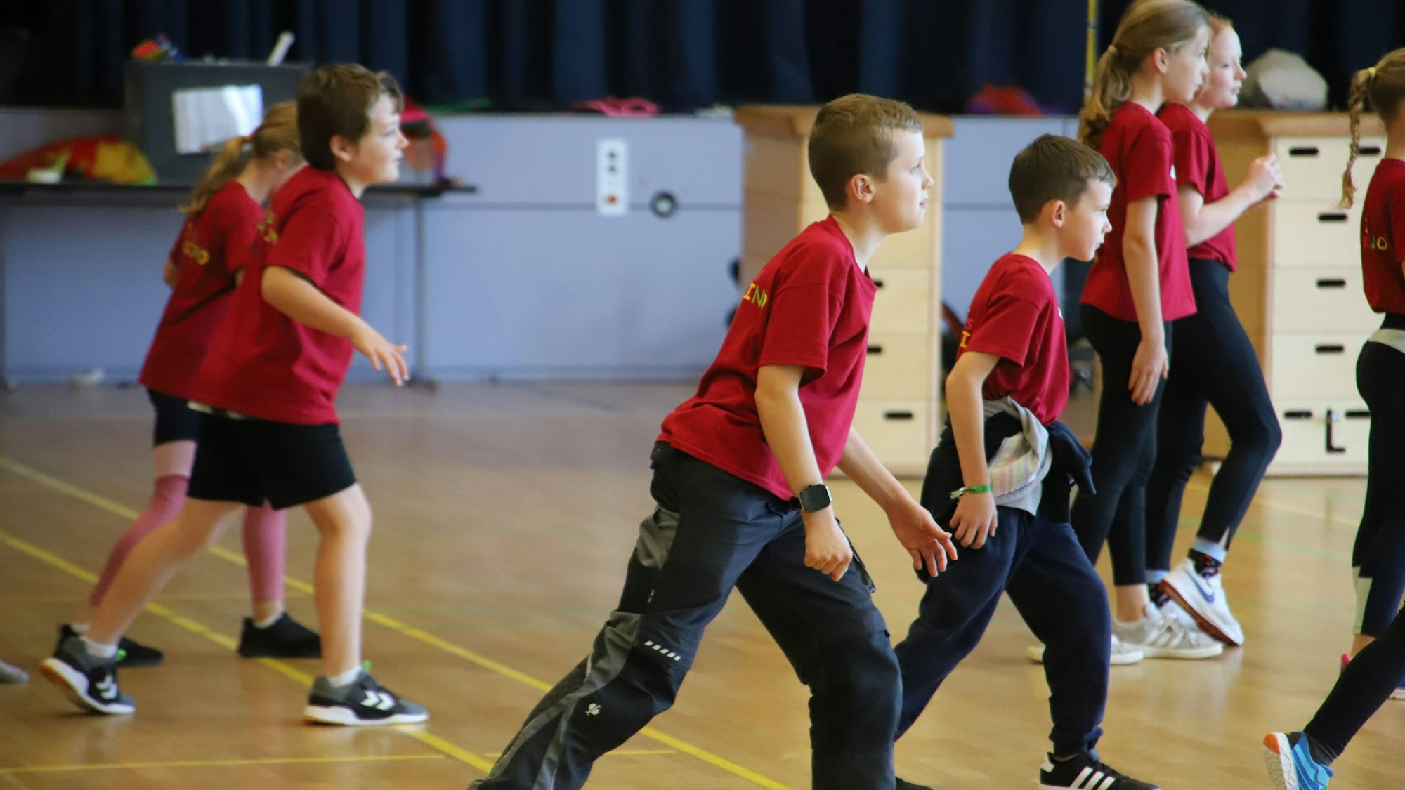 Kinder laufen durch eine Turnhalle.