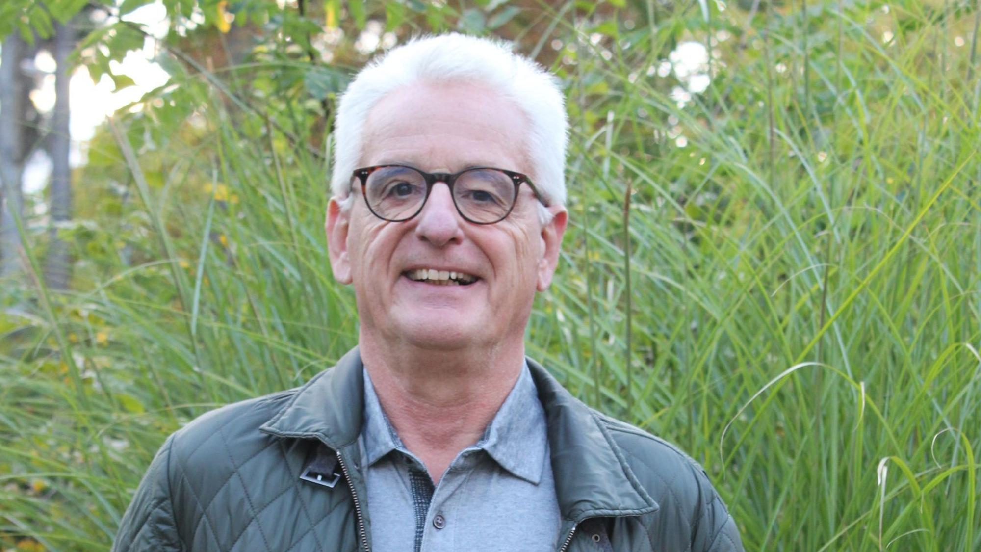 Der Autor steht draußen in der freien Natur, hinter ihm wächst hohes Gras.