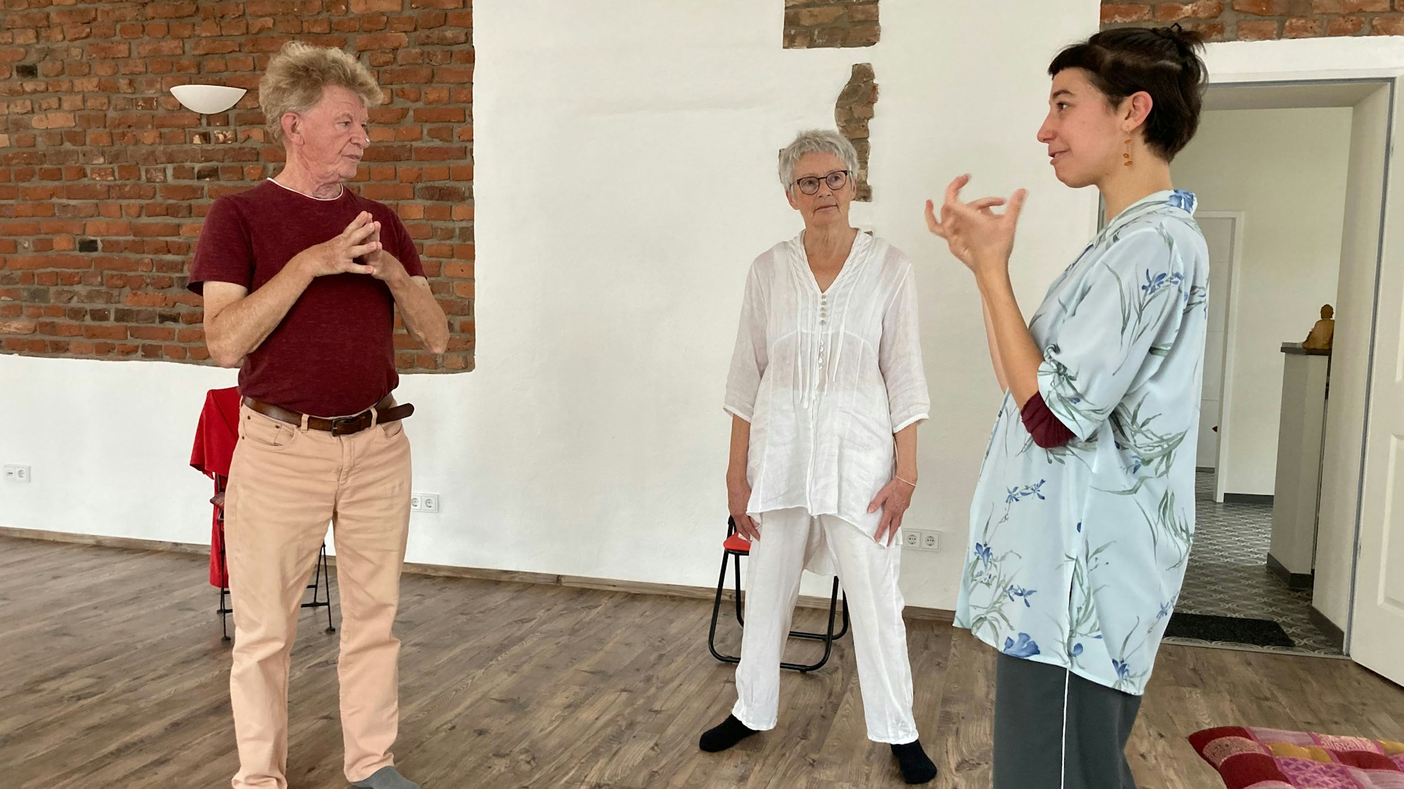 Ein älterer Herr und eine ältere Frau sprechen mit einer Frau.