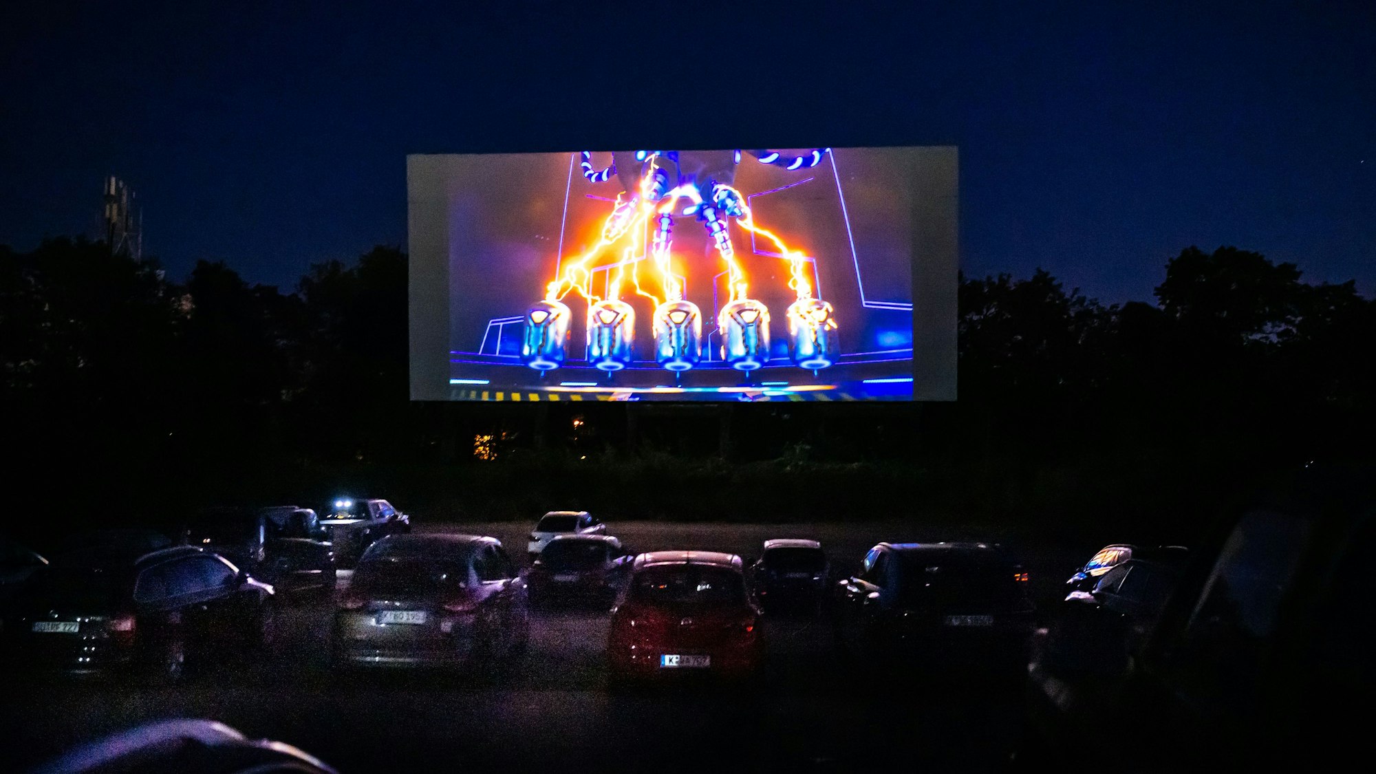 Autos stehen vor einer großen Leinwand