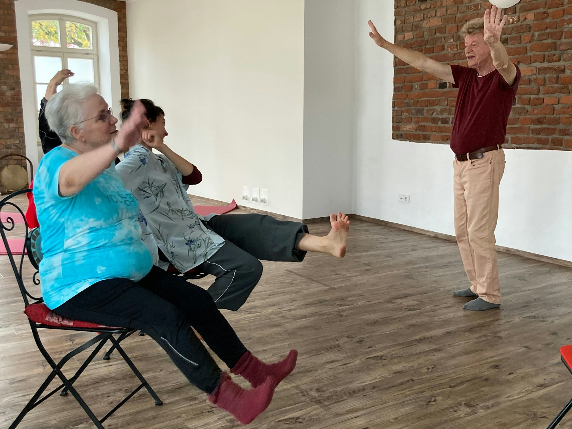 Ein Mann steht vor mehreren Menschen, die sich auf Stühlen bewegen.