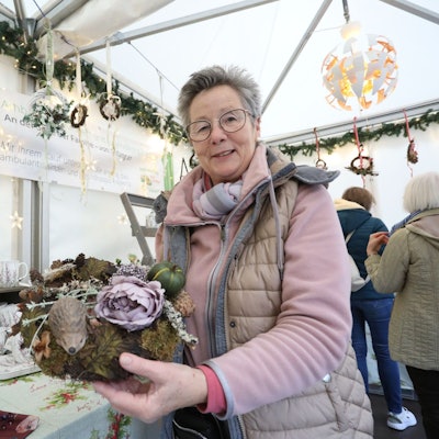 Eine Frau zeigt ein Blumengesteck.