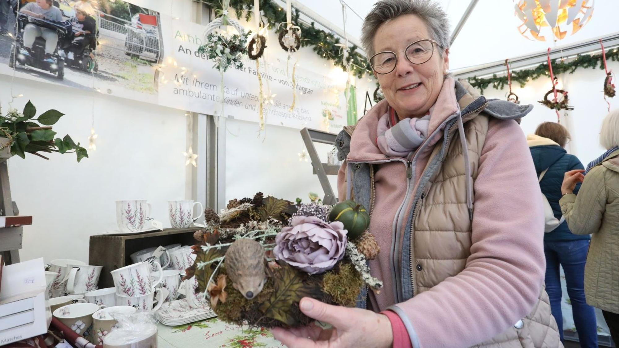 Eine Frau zeigt ein Blumengesteck.