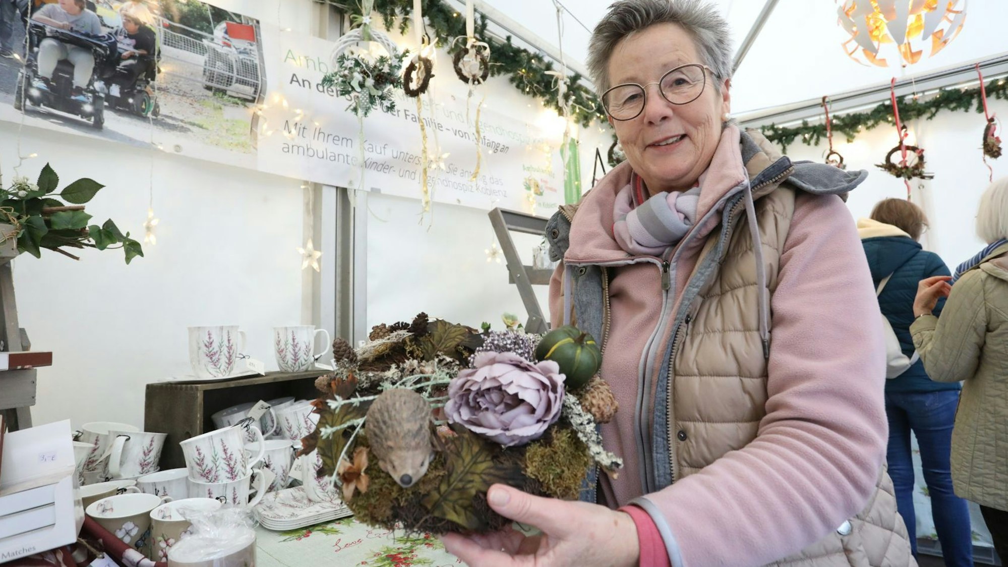 Eine Frau zeigt ein Blumengesteck.