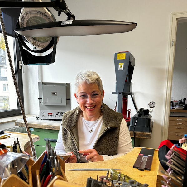 Angela Klussmann sitzt in ihrer Werkstatt, in der sie Schmuck herstellt.