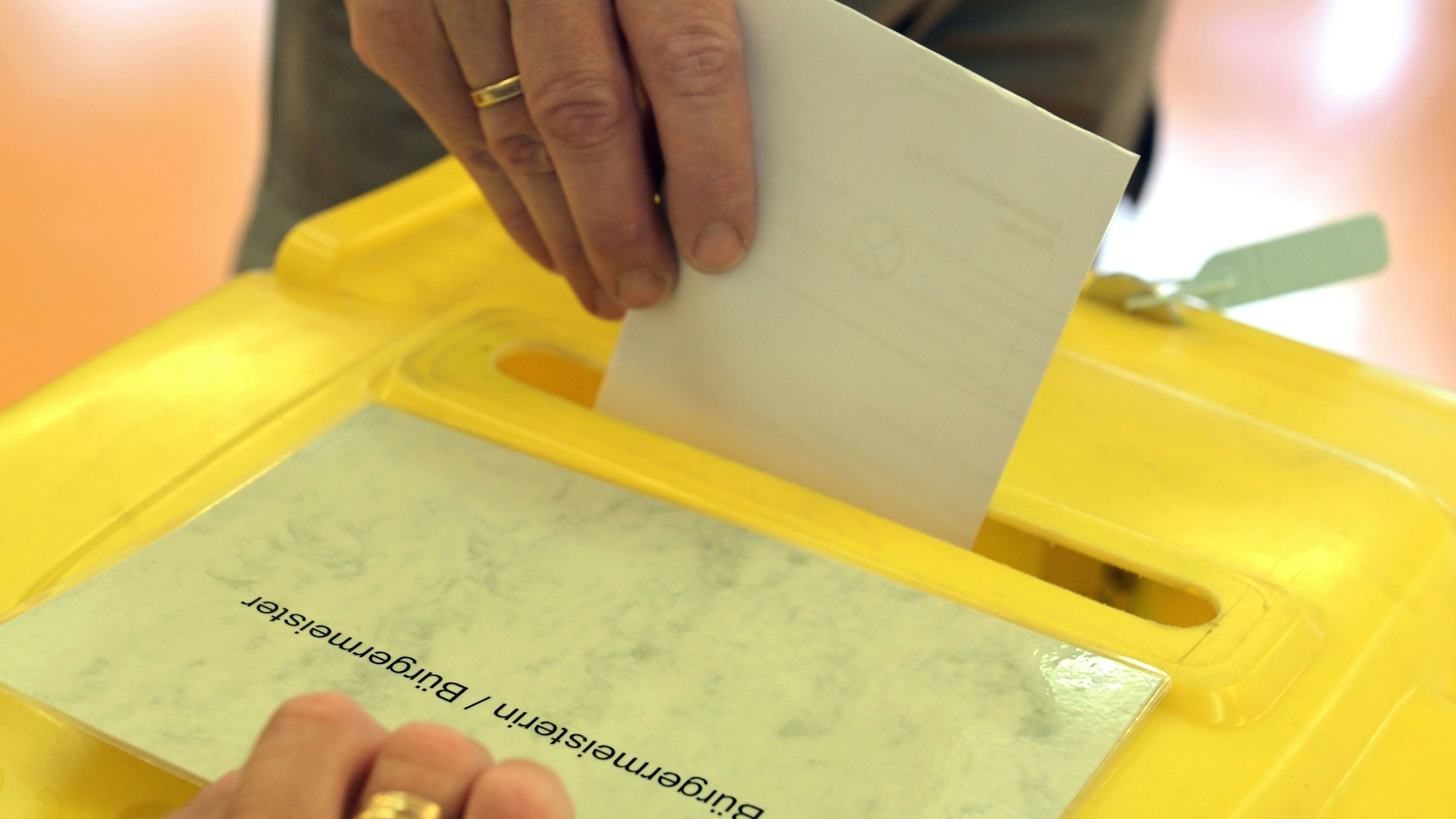 Ein Stimmzettel wird in eine Wahlurne gesteckt.