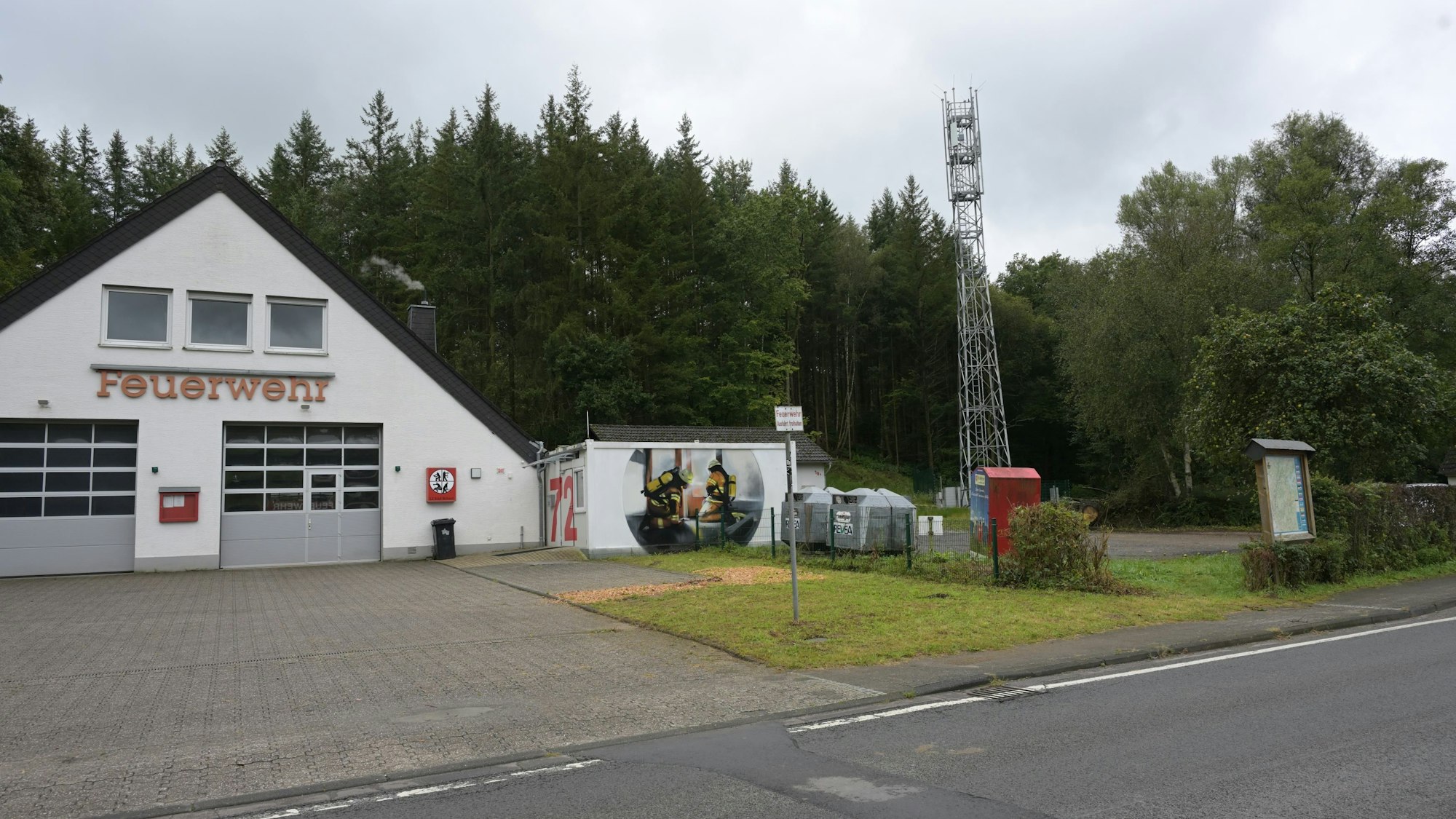 Ein Feuerwehrgerätehaus, daneben ein Parkplatz.