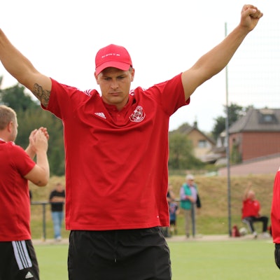 Zülpichs Trainer David Sasse jubelt mit erhobenen Armen, aber ausdrucklosem Gesicht.