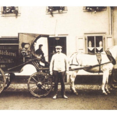 Zu sehen ist eine Schwarz-Weiß-Aufnahme eines Mannes vor einer Kutsche.